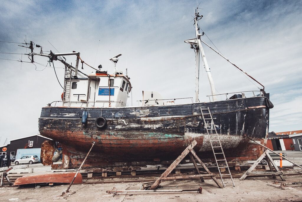 Rust, Barnacles, and Corrosion: Battling the Elements and Wear on Vessel Surfaces 11 brown and white ship on brown sand during daytime